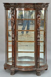 Oak crystal cabinet with serpentine glass door,  flanked by caryatids on carved columns with mirror back and glass shelves, set on p...