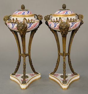 Pair of Sevres covered urns mounted in bronze supports, 
Classical face, legs ending in hoof feet, set on triangular porcelain base ...