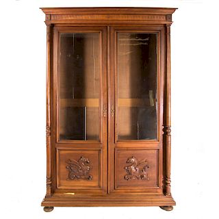 Librero. Francia. Siglo XX. Estilo Enrique II. En madera tallada de nogal. Con 2 puertas de cristal y fustes compuestos.