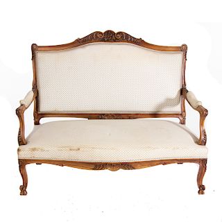 Love seat. Francia. SIglo XX. Estilo Luis XV. En talla de madera de nogal. Con tapicerÌa de tela color beige. Respaldo cerrado.