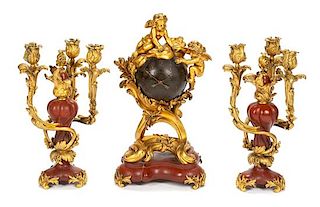 A French Gilt Bronze and Rouge Marble Clock Garniture Height of mantel clock 19 inches; height of candelabra 15 inches.