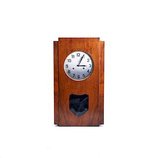 Reloj de pared. Alemania, siglo XX. De la firma Junghans. Caja de madera tallada. Mecanismo de cuerda y péndulo. Carátula metálica.