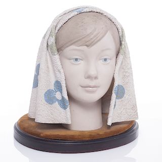 Busto de niña con manto. Siglo XX. Elaborado en porcelana policromada. Con base de madera y terciopelo. Presenta manchas.