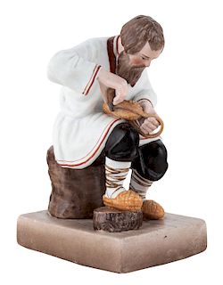 A RUSSIAN PORCELAIN FIGURE OF A BAST SHOE MAKER, GARDNER PORCELAIN FACTORY, MOSCOW, LATE 19TH CENTURY