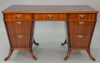 Mahogany desk with red tooled leather top having center drawer flanked by three drawers, length 53 inches.