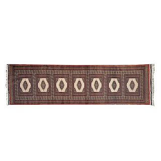 Tapete de pasillo. Siglo XX. Estilo Bokhara. Elaborada en lana y algodón. Decorada con diseños romboidales sobre fondo café.
