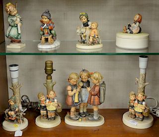 Eight large Hummel figurines to include three lamps, one with girls; a round box; boy on sled; candlelight; and two kids with donkey...