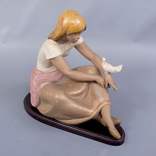 Mujer con paloma. España. Siglo XX. Elaborada en porcelana Lladró. Acabado gres. Con base de madera tallada.
