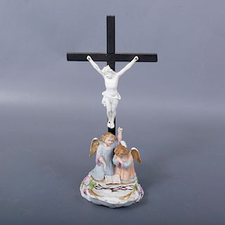 Cristo con ángeles. Siglo XX. Elaborados en porcelana. Con cruz de madera tallada. Decorados con esmalte dorado y elementos orgánico...