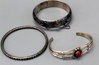 Three sterling silver bangles. One with red coral
