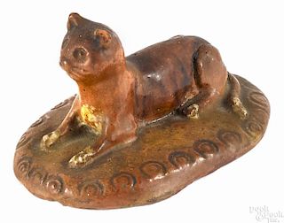 Pennsylvania recumbent redware cat, 19th c., with cream colored paws and lying on an oblong base