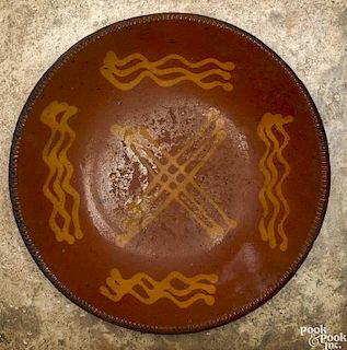 Redware charger, 19th c., with yellow slip X surrounded by wavy lines, 12 1/2'' dia.