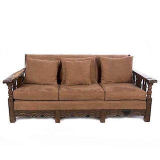 Sofá de tres plazas. Siglo XX. En talla de madera. Con tapicería de tela color marrón. Respaldo cerrado y soportes lisos.