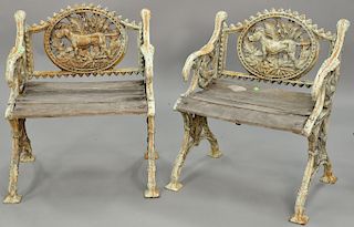 Pair of cast iron outdoor armchairs having dog on oval back splat, bird head armrest and flying bird arms.