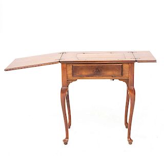 Mesa, Siglo XX. Elaborada en madera tallada. Cubierta rectangular abatible, cajón costurero central y soportes curvos.