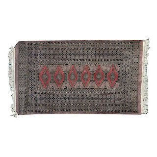 Tapete de oración. Siglo XX.Estilo Bokhara. Anudado a mano en fibras de lana y algodón. Decorada con diseños romboidales y geométricos.