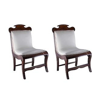 Par de sillas bajas. Siglo XX. Elaboradas en madera tallada. Respaldo y asiento acojinado en textil blanco y soportes semicurvos.