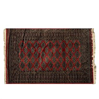 Tapete. Pakistán, siglo XX. Estilo Bokahara. Anudado a mano en fibras de lana. Decorado con motivos geométricos sobre fondo rojo.