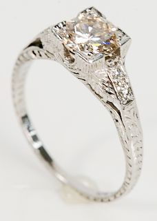 Platinum and diamond engagement ring having center diamond approximately .75 cts. flanked by 2 small diamonds on either side in carv...