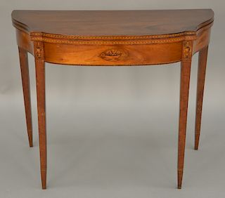 Federal mahogany game table, table having bowed shaped top over conforming frieze with urn panel inlays, set on square tapered legs...