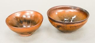 Two hair’s-fur stoneware (jian yao) tea bowls, China, the stoneware bodies covered overall with vertical striated brownish glaze upo...