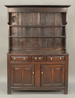 George II oak cupboard in two parts, upper portion with shelves on lower portion with three drawers over two doors, on square legs,...