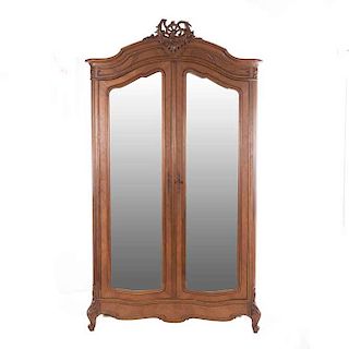 Armario. Francia. Siglo XX. Estilo Luis XV. En talla de madera de nogal. Con par de puertas con espejo de luna irregular biselada.