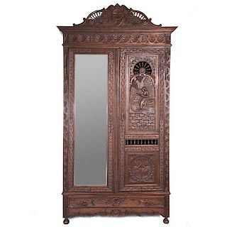 Armario. Francia. Siglo XX. Estilo Bretón.  En talla de madera de roble. Par de puertas, una con espejo de luna rectangular biselada.