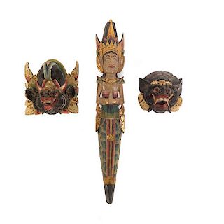 Lote de 3 figuras decorativas. Indonesia. SXX. En talla de madera. Decoradas con esmalte dorado. Consta de: par de máscaras y deidad.