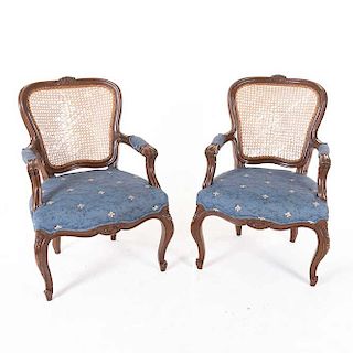Par de sillones. Siglo XX. En talla de madera. Con respaldo de bejuco, asiento de tela floreada color azul y soportes tipo cabriolé.