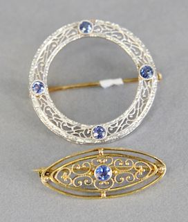 Two pins one platinum and gold circle with sapphires and other is 14 karat gold oval with sapphire.
