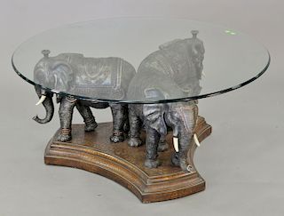 Coffee table with triple elephant base and glass top.ht. 20 in., dia. 44 in.