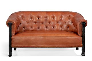 A parcel ebonized and tufted leather library sofa