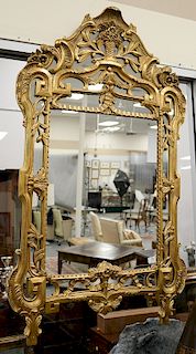 Continental Rococo style giltwood mirror, foliate frame and surmounted by a crest with a flower filled urn. ht. 59 in., wd. 34 1/2 i...