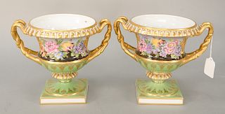 Pair of porcelain urns with painted flowers and gilt gold on green base, bottom having crown over sword mark. ht. 7 in., wd. 8 in.  Provenance: From t