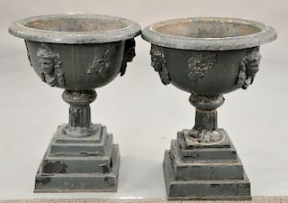 Victorian iron urns with face (one small chip in base of urn, one in need of repair). ht. 24 in., dia. 30 in. Provenance: From the E...