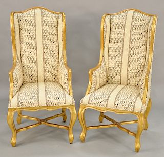 Pair of French Provincial style upholstered gold painted bergeres on cabriole legs joined by X-form stretcher. ht. 51 in. Provenance...