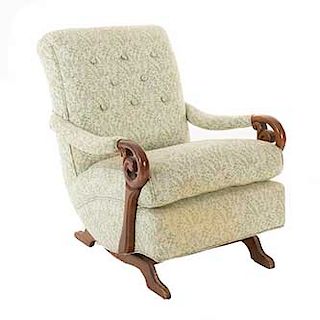 Sillón-mecedora. Siglo XX. En talla de madera y tapiz de tela. Respaldo capitonado, asiento tapizado y soportes semicurvos.
