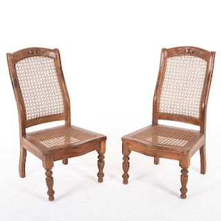 Par de sillas. Siglo XX. En talla de madera. Con respaldos y asientos de bejuco. Con fustes y soportes compuestos.