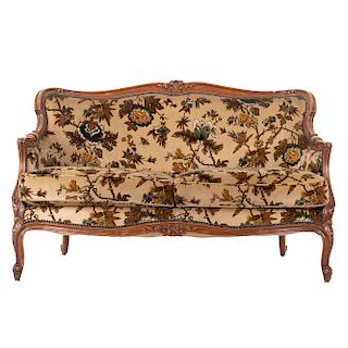 Sofá. Francia. Siglo XX. Estilo Luis XV. En talla de madera de nogal. Con respaldo cerrado y asientos acojinados en tapicería.