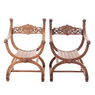 Par de curules. Francia. Siglo XX. En talla de madera de nogal. Con respaldos abiertos, asientos de madera, chambrana en "H".
