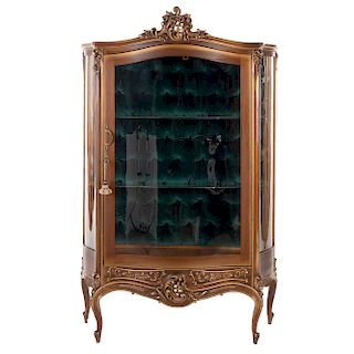 Vitrina. Siglo XX. Estilo Luis XV. En talla de madera con esmalte dorado. Con puerta abatible y costados de cristal, 2 entrepaños.