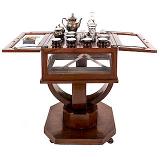Mesa-exhibidor y juego de té. Siglo XX. Mesa en talla de madera. Con puertas superiores abatibles con cristal biselado.