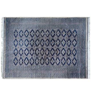 Tapete. Pakistán, siglo XX. Estilo Bokhara. Elaborado en fibras de lana y algodón. Decorado con motivos geométricos sobre fondo gris.