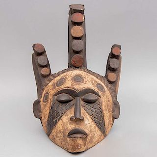 Máscara de casco. Nigeria, Siglo XX. Grupo étnico Igbo. Talla en madera, pigmentos y caolín. Decorada con tocado tradicional Igbo.
