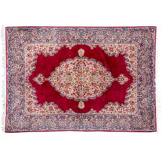 Tapete. Persia, siglo XX. Estilo Ghom. Anudado a mano en fibras de lana y algodón. Decorada con motivos florales y orgánicos.