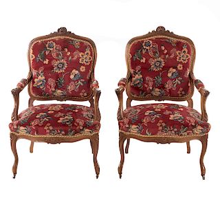 Par de sillones. Francia. SXX. Estilo Luis XV. En talla de madera de nogal. Con respaldos cerrados y asientos en tapicería color rojo.