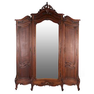 Armario. Francia. SXX. Estilo Luis XV. En talla de madera de nogal. Con 3 puertas abatibles, una con espejo de luna irregular biselada.