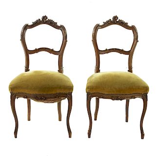 Par de sillas. Francia. SXX. Estilo Luis XV. En talla de madera de nogal. Con respaldos abiertos, asientos en tapicería color verde.