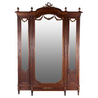 Armario. Francia. Siglo XX. Estilo Luis XVI. En talla de madera de nogal. 3 puertas abatibles, con espejos de luna irregular biselada.